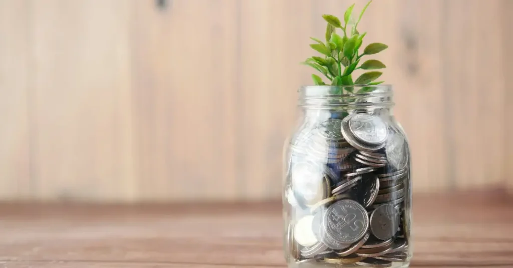 برطمان زجاجي مليء بالعملات المعدنية وينمو منه نبات أخضر يرمز لتوزيع الراتب وقاعدة 50/30/20
